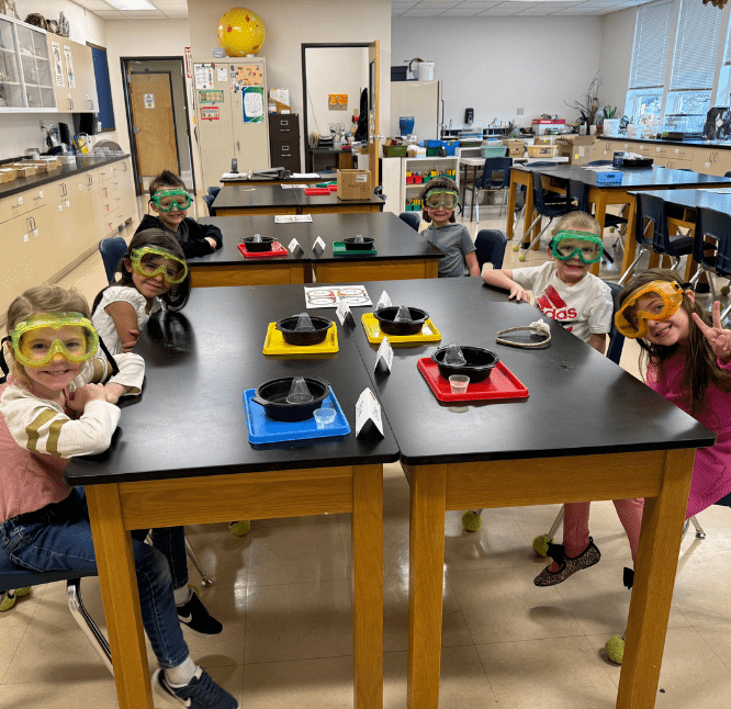 Happy elementary students with goggles in the classroom, eager to start a science project.