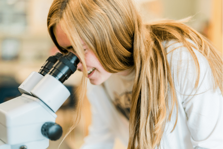 High school student prepares for her future professional career whilst examining a specimen underneath a microscope.