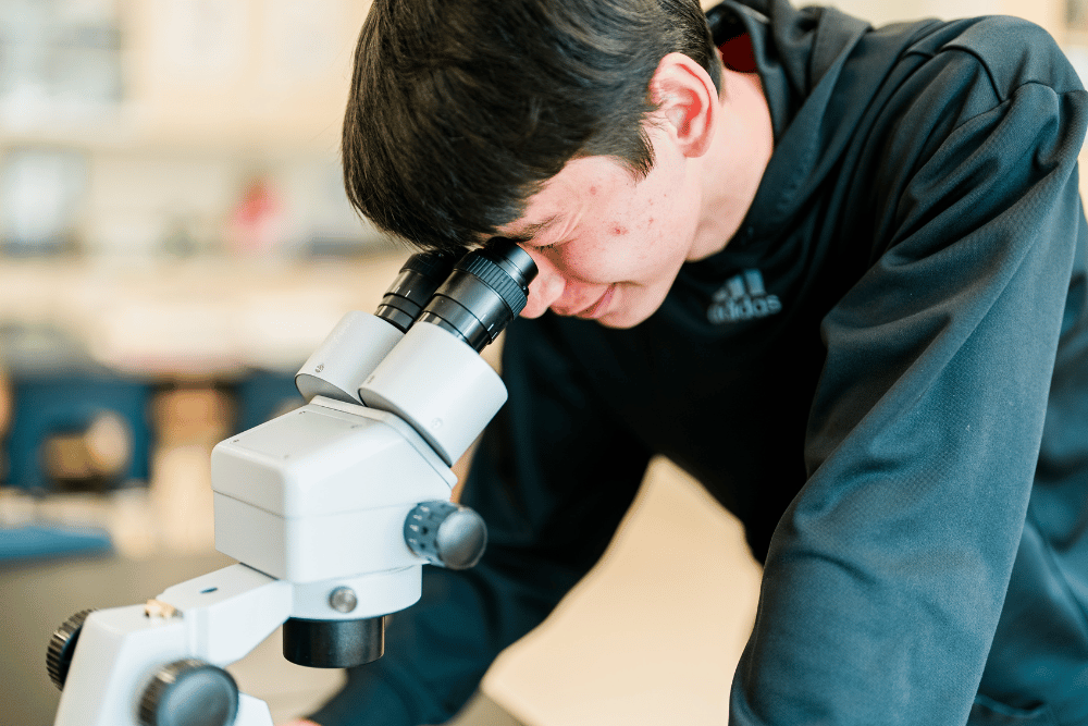A high school boy observing through a microscope.
