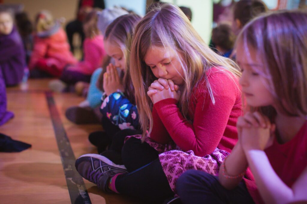 Elementary girls bow their heads in prayer in chapel service at West Hills Christian School.