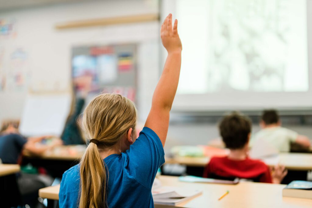Girl student raises hand in class in Portland area school.