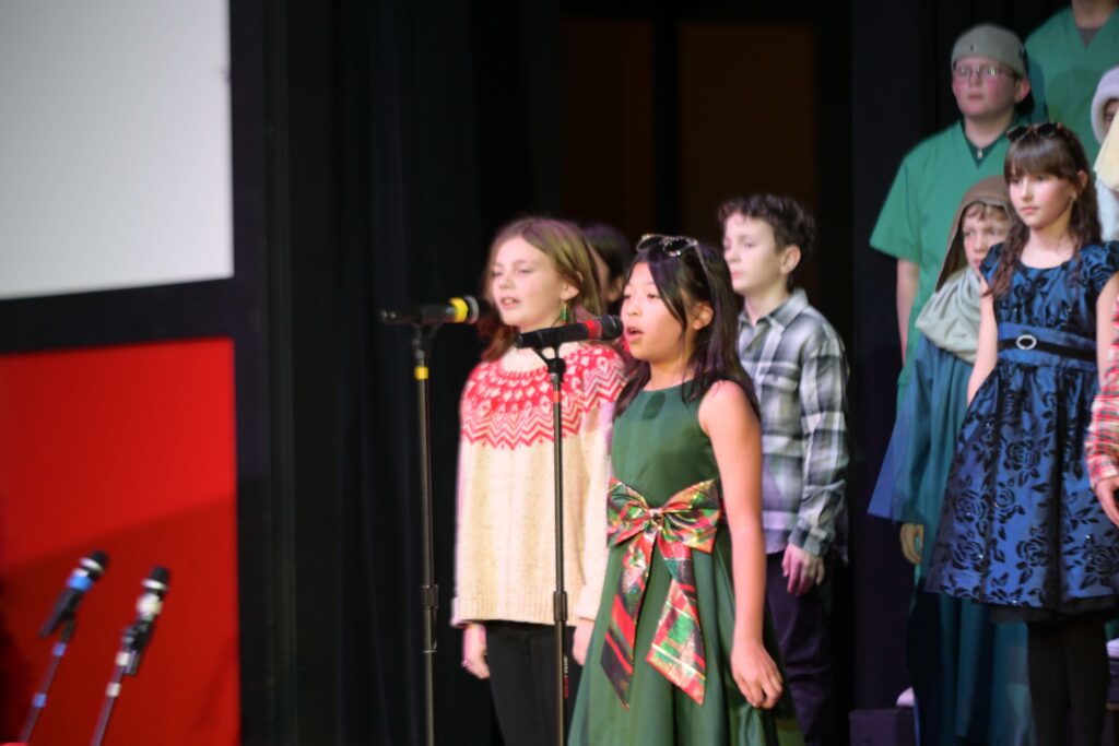 This picture shows two elementary students singing in part of their choral group.