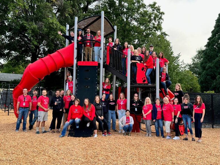 A group photo of the staff at West Hills on the new playground.
