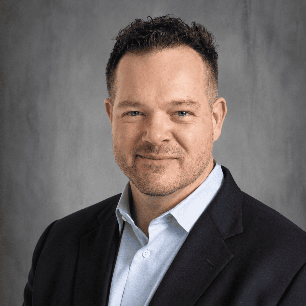 John Ewert, a professional with a friendly smile, wears a suit jacket and light blue shirt.